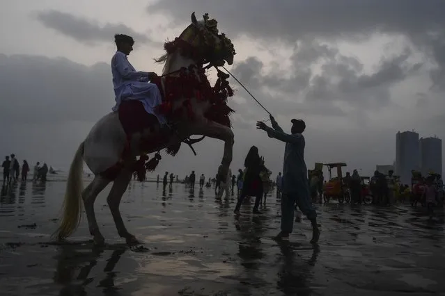 A youth rides a horse at the Clifton beach in the port city of Karachi on June 21, 2021, after the government eased restrictions to curb the spread of the Covid-19 coronavirus. (Photo by Asif Hassan/AFP Photo)