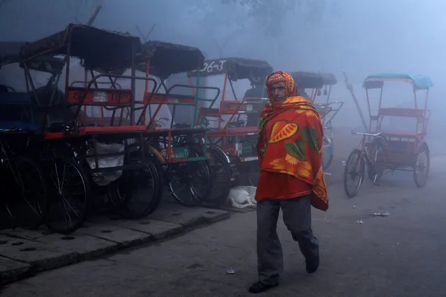 A man wrapped in blanket walks along a street on a foggy morning in the old quarters of Delhi, India, December 31, 2018. (Photo by Anushree Fadnavis/Reuters)