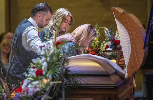 Tracey Walker leans into the coffin of her husband, Joe Walker, who was killed at Schmengees Bar and Grill in the mass shooting Friday, November 17, 2023 in Auburn, Maine. Joe's children, Brandon and Bethany Welsh stand with her in support at the funeral at the East Auburn Baptist Church. (Photob by Andree Kehn/Sun Journal via AP Photo)