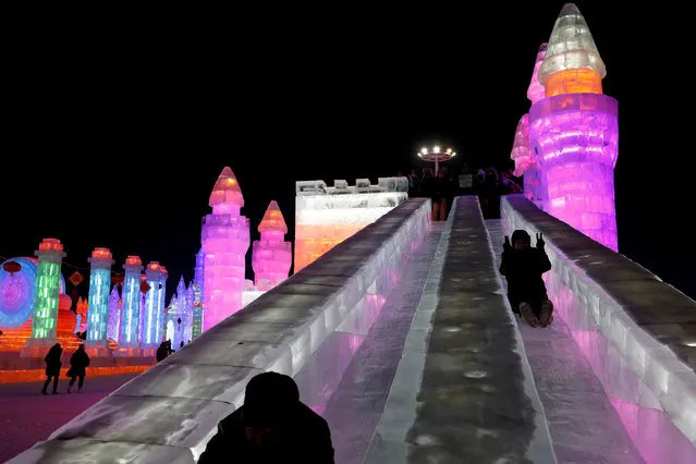 Visitors ride a slide in front of ice sculptures illuminated by coloured lights during the annual ice festival in Harbin, Heilongjiang province, China January 5, 2019. (Photo by Tyrone Siu/Reuters)