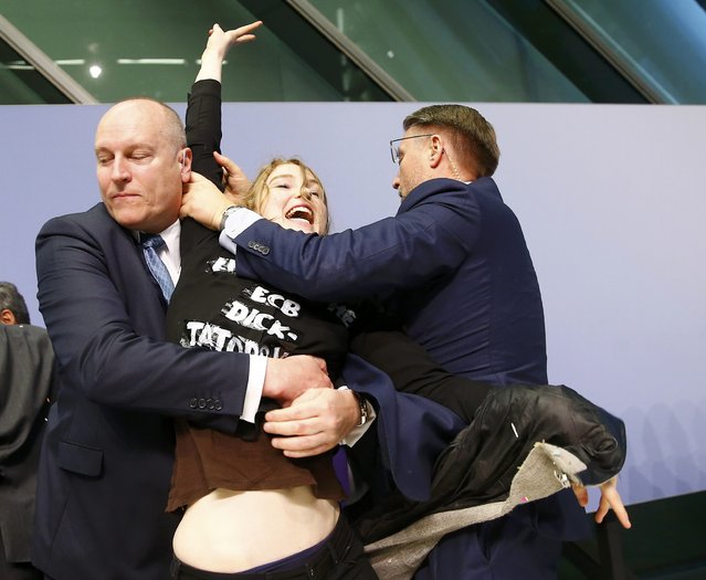 Security officers detain a protester who jumped on the table in front of the European Central Bank President Mario Draghi during a news conference in Frankfurt, April 15, 2015. (Photo by Kai Pfaffenbach/Reuters)