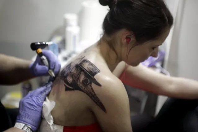 An artist draws a tattoo on a woman's back during a tattoo convention in Ljubljana April 18, 2015. (Photo by Srdjan Zivulovic/Reuters)