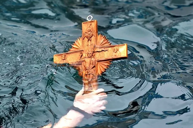 A man retrieves a wooden cross from the sea during the ceremony of the blessing of the waters marking the orthodox Epiphany Day at the port of Aiegina island near Athens on January 6, 2014. (Photo by Louisa Gouliamaki/AFP Photo)