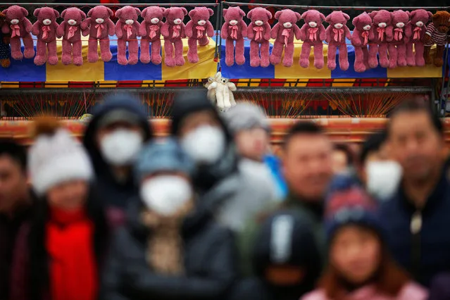 Toys hang behind people, some wearing face mask against pollution, following performers during a re-enactment of an ancient Qing Dynasty ceremony as the Lunar New Year of the Rooster is celebrated at the temple fair at Ditan Park (the Temple of Earth), in Beijing, China January 28, 2017. (Photo by Damir Sagolj/Reuters)