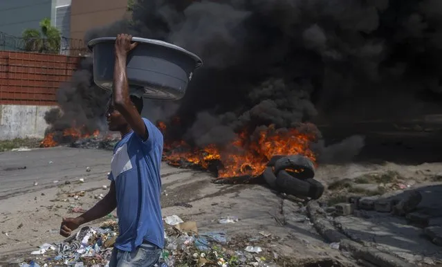Burning tires block a road, set by protesters in Port-au-Prince, Haiti, Monday, October 18, 2021. Workers angry about the nation’s lack of security went on strike in protest two days after 17 members of a U.S.-based missionary group were abducted by a violent gang. (Photo by Joseph Odelyn/AP Photo)