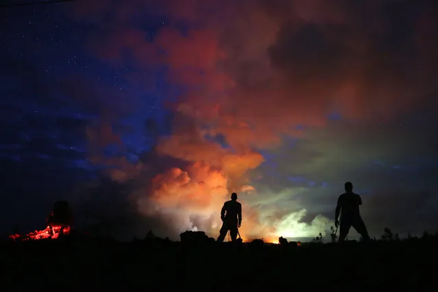Photographers work as lava from active fissures illuminates volcanic gases from the Kilauea volcano on Hawaii's Big Island on May 15, 2018 in Hawaii Volcanoes National Park, Hawaii. The U.S. Geological Survey said a recent lowering of the lava lake at the volcano's Halemaumau crater 'has raised the potential for explosive eruptions' at the volcano.  (Photo by Mario Tama/Getty Images)