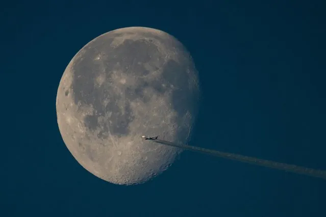 A plane passes in front of the setting moon on January 21, 2022 in London, England. (Photo by Dan Kitwood/Getty Images)