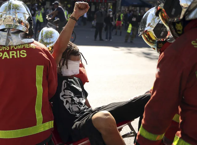 An injured man raises his fist as he is carried away by emergency personnel during a yellow vest demonstration in Paris, Saturday, April 20, 2019. French yellow vest protesters are marching anew to remind the government that rebuilding the fire-ravaged Notre Dame Cathedral isn't the only problem the nation needs to solve. (Photo by Francisco Seco/AP Photo)