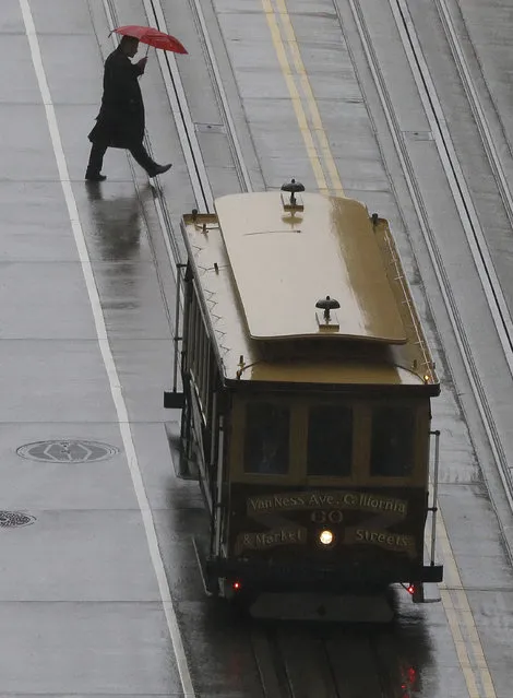A pedestrian crosses the street behind a Cable Car in San Francisco, Friday, March 4, 2016. (Photo by Jeff Chiu/AP Photo)