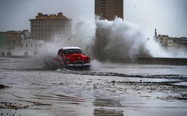 An old American car passes along the flooded malecon due to a cold front in Havanna, on February 5, 2024. (Photo by Yamil Lage/AFP Photo)