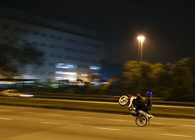 A motorcyclist performs a wheelie on a highway in Kuala Lumpur, Malaysia, October 17, 2015. (Photo by Olivia Harris/Reuters)