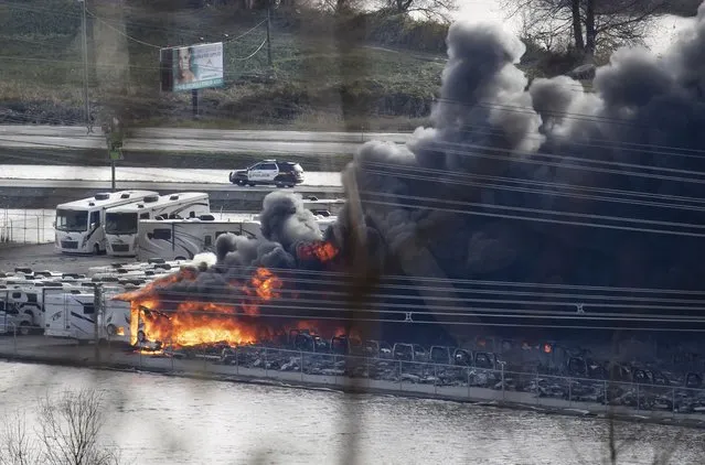 Recreational vehicles burn during a fire at a business surrounded by floodwaters in Abbotsford, British Columbia, on Wednesday, November 17, 2021. (Photo by Darryl Dyck/The Canadian Press via AP Photo)