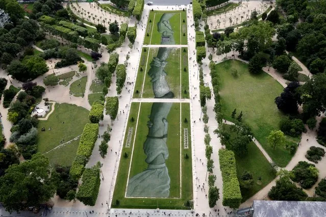 A giant fresco painted on the “Champs de Mars” lawn by French street artist Saype is seen from the Eiffel Tower on June 14, 2019 in Paris, France. The 600 metre long fresco, painted on the Champs de Mars lawn, pays tribute to the work of the “SOS Mediterranee” migrant charity association. This artwork is seen for the first time in front of the Eiffel Tower, before being reproduced throughout the world for three years in the cities of Geneva, Berlin, Belfast, Buenos Aires, Christchurch, London, Melbourne, New York and Nairobi. (Photo by Philippe Wojazer/Reuters)