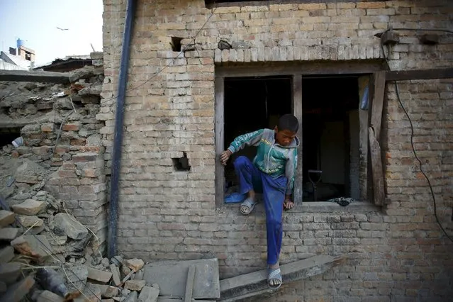 A boy exits from the window of his house as he works to clear debris, a month after the April 25 earthquake in Kathmandu, Nepal May 25, 2015. (Photo by Navesh Chitrakar/Reuters)