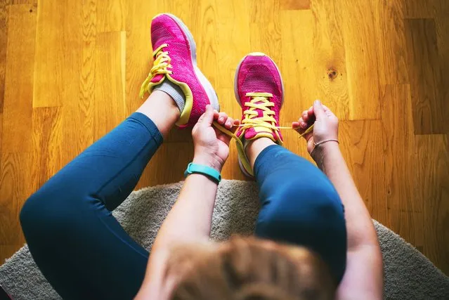 Young sporty woman with smart watch tying shoelaces. (Photo by Emilija Manevska/Getty Images)