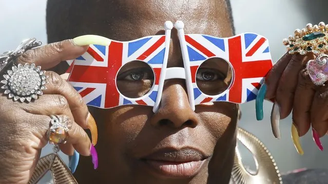 A royal fan adjusts her Union flag glasses, in Windsor, England, Wednesday, April 20, 2016. Royal fans are gathering in Windsor ahead of Thursday's celebrations for the 90th birthday of Britain's Queen Elizabeth II. (Photo by Kirsty Wigglesworth/AP Photo)