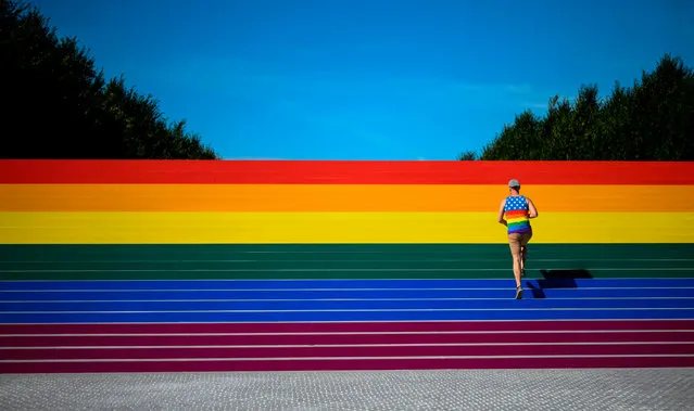 A man walks on steps covered in rainbow colors for Pride Month at Franklin D. Roosevelt Four Freedoms Park on June 15, 2019 in New York City. Organizers claim it is the largest LGBT pride flag in New York City and measures around 12 by 100 feet (3.6 x 30 meters). (Photo by Johannes Eisele/AFP Photo)