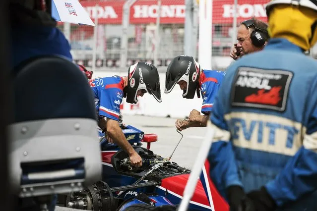 The pit team for Takuma Sato of Japan make adjustments during practice for the IndyCar auto race Saturday, June 13, 2015, in Toronto. (Aaron Vincent Elkaim/The Canadian Press via AP)