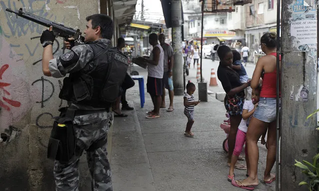 A police officer takes up position during an operation at the Mare slums complex in Rio de Janeiro March 25, 2014. (Photo by Ricardo Moraes/Reuters)