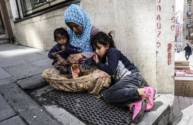 A Syrian woman sits with her children on the sidewalk, in downtown Istanbul on April 22, 2014. The number of Syrian refugees in Turkey has reached “almost one million”, Prime Minister Recep Tayyip Erdogan has said, while pledging to keep accepting those fleeing the war. The three-year conflict in Syria has sent millions fleeing to neighbouring countries and beyond. (Photo by Bulent Kilic/AFP Photo)