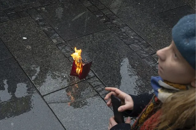 A Russian passport burns on the street during a protest against the Russian military invasion of Ukraine, in Belgrade, Serbia, Sunday, March 6, 2022. A group of Russian citizens living in Serbia were among dozens of people on Sunday who braved freezing weather and a late winter blizzard to gather in central Belgrade in support of Ukraine and against the war that in the past 11 days has claimed scores of lives and driven 1.5 million people from their homes. (Photo by Marko Drobnjakovic/AP Photo)