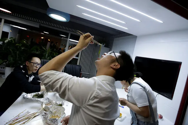 Yu Xiaojian, an employee at Goopal Group, eats with his colleagues during a break at work around midnight, in Beijing, China, April 19, 2016. (Photo by Jason Lee/Reuters)