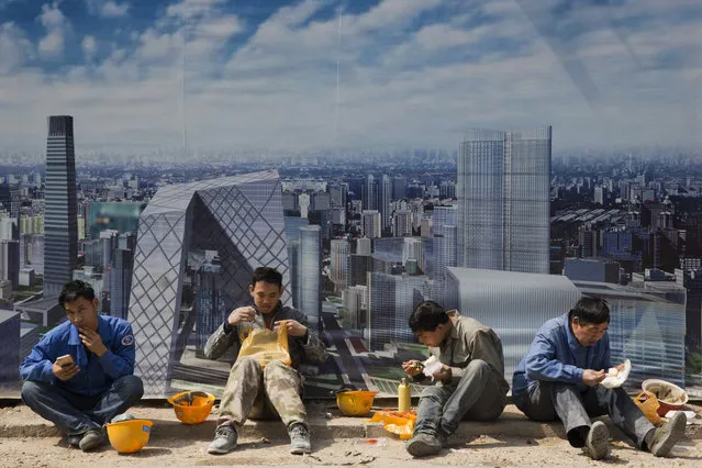 Construction workers eat lunch near a board with an artist's impression of the Central Business District outside a construction site in Beijing, China, Thursday, April 6, 2017. Asia's developing economies will see steady growth this year and the next, though the evolving policies of President Donald Trump's administration are a major uncertainty, the Asian Development Bank said in a report Thursday. It said 30 of the 45 countries covered in the report will see sustained growth that will help offset the gradual slowdown in China, Asia's biggest economy. (Photo by Ng Han Guan/AP Photo)