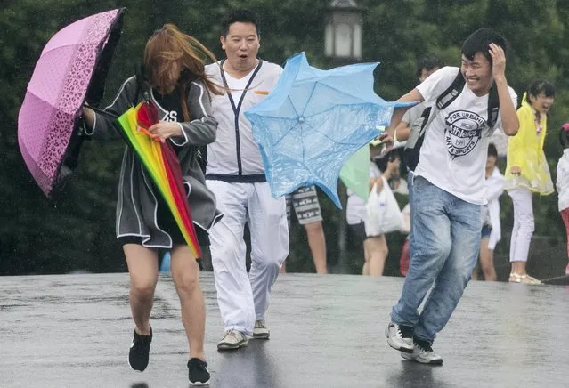 Tourists hold umbrellas as they tour the West Lake against strong wind under the influence of Typhoon Chan-hom, in Hangzhou, Zhejiang province, China, July 11, 2015. One of the most powerful typhoons to strike eastern China in decades disrupted air, rail and sea transport on Saturday after forcing the evacuation of more than a million people from the provinces of Zhejiang and Jiangsu, state media reported. (Photo by Reuters/Stringer)