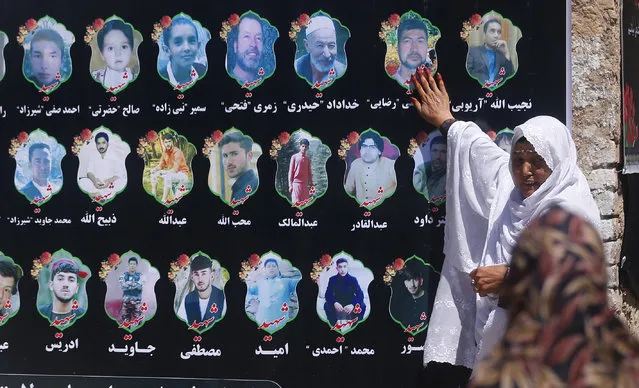 An Afghan woman cries as she touches a banner displaying photographs of victims of the Dubai City wedding hall bombing during a memorial service in Kabul, Afghanistan, Tuesday, August 20, 2019. The deadly bombing at a wedding in Afghanistan's capital late last Saturday that killed dozens of people was a stark reminder that the war-weary country faces daily threats not only from the long-established Taliban but also from a brutal local affiliate of the Islamic State group, which claimed responsibility for the attack. (Photo by Rafiq Maqbool/AP Photo)