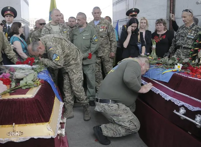 Ukrainian soldiers pay the last tributes to the coffins bearing the bodies of Sergiy Baula and Mykola Kuliba, soldiers who were killed in the war conflict-hit Donetsk region, during a commemoration ceremony in Independence Square in Kiev, Ukraine, on Thursday, May. 26, 2016. Baula and Kuliba were killed on May 24 from the fire by pro-Russian separatists. (Photo by Efrem Lukatsky/AP Photo)