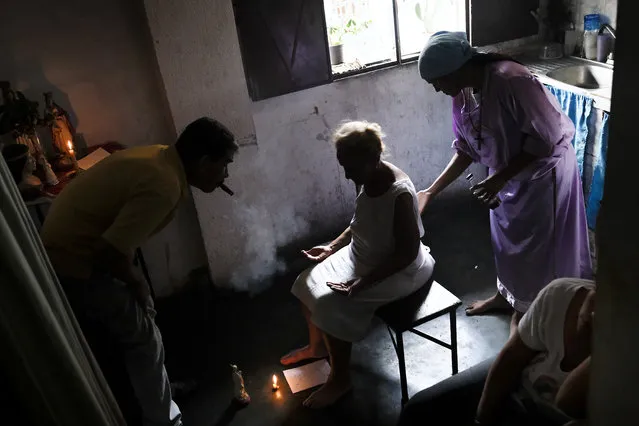Venezuelan Esperanza Castillo (C), 74, is teated at the clinic of Venezuelan spiritual healer “Guayanese Brother” in Petare neighborhood, Caracas, on September 25, 2019. Venezuelans turn to alternative treatments and the use of herbs to alleviate the disease conditions due to the lack or high cost of medicines. (Photo by Matias Delacroix/AFP Photo)