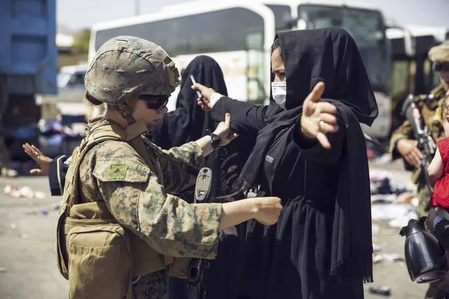 In this image provided by the U.S. Marine Corps, a Marine with the 24th Marine Expeditionary Unit (MEU) checks an Afghan woman as she goes through the evacuation control center at Hamid Karzai International Airport in Kabul, Afghanistan, Saturday, August 28, 2021. (Photo by Staff Sgt. Victor Mancilla/U.S. Marine Corps via AP Photo)