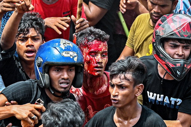 New Market traders rescue an injured shopkeeper who got hurt during a clash with students from Dhaka college in Dhaka on April 19, 2022. (Photo by Munir Uz Zaman/AFP Photo)