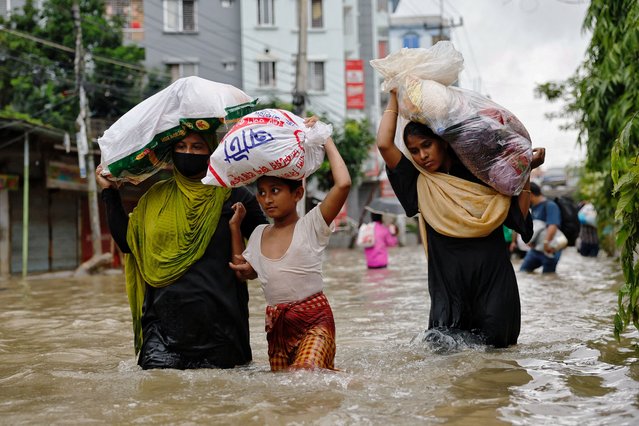 People wade through water as they carry relief supplies amid severe flooding in Feni, Bangladesh, on August 25, 2024. (Photo by Mohammad Ponir Hossain/Reuters)