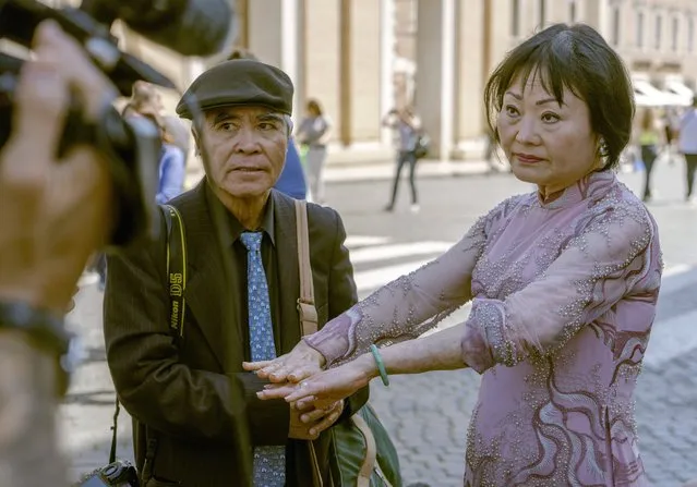 Pulitzer Prize-winning photographer Nick Ut, left, looks at Kim Phuc showing to cameras the scars left by napalm on her body after they met with Pope Francis during the papal weekly general audience in St. Peter's Square at The Vatican, Wednesday, May 11, 2022. Ut and UNESCO Ambassador Kim Phuc are in Italy to promote the photo exhibition “From Hell to Hollywood” resuming Ut's 51 years of work at the Associated Press, including the 1973 Pulitzer-winning photo of Kim Phuc fleeing her village after it was accidentally hit by napalm bombs dropped by South Vietnamese forces. (Photo by Domenico Stinellis/AP Photo)