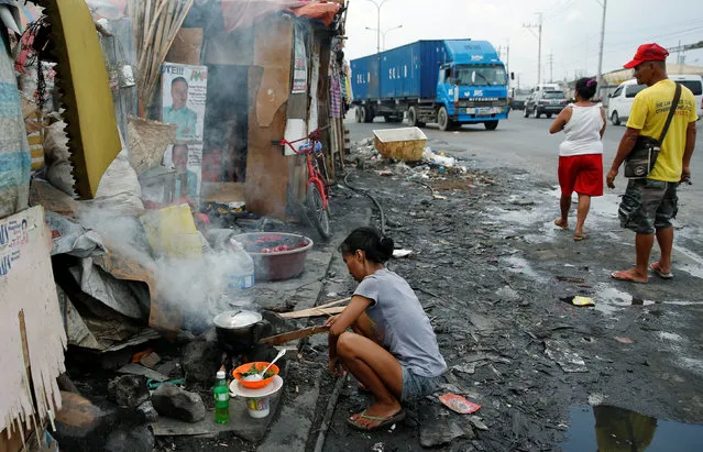 A housewife whose family lives in a shanty cooks beside a road in Manila, Philippines May 25, 2016. (Photo by Erik De Castro/Reuters)