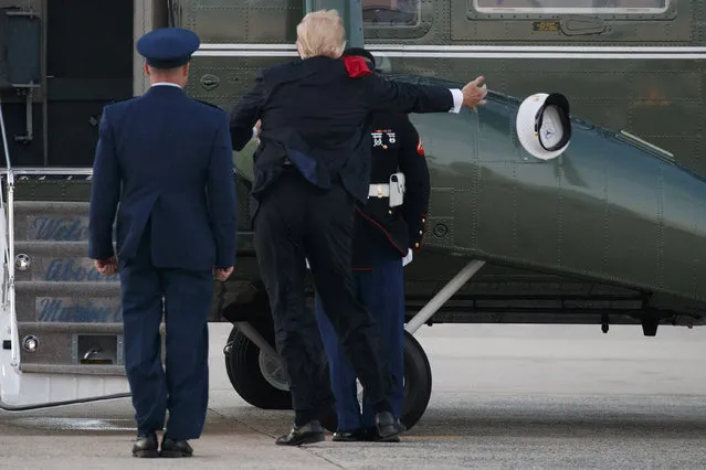A Marine guards cover blows away as President Donald Trump attempts to put it on his head during an arrival at Andrews Air Force Base, Saturday, July 8, 2017, in Andrews Air Force Base, Md. (Photo by Evan Vucci/AP Photo)