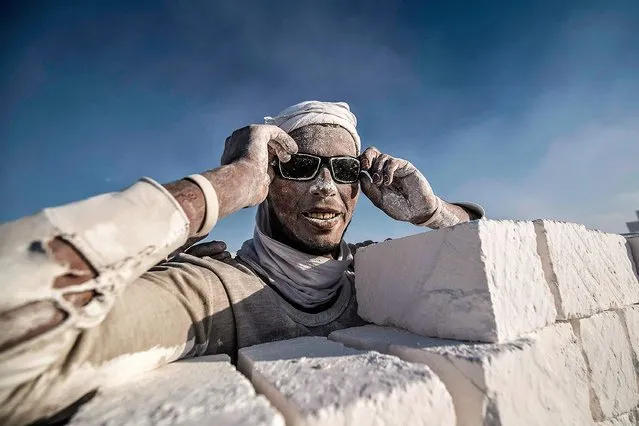 A labourer poses for a picture at the “White Mountain” limestone extraction quarry site near Egypt's southern city of Minya, some 265 kilometres south of the capital, on December 7, 2019. Covered in fine white dust, labourers at a limestone quarry in southern Egypt toil in brutal conditions with little workplace safety for paltry pay. Labourers work in shifts at the quarry in the so-called White Mountain east of the river Nile outside Minya, about 265 km south of the capital Cairo. (Photo by Khaled Desouki/AFP Photo)