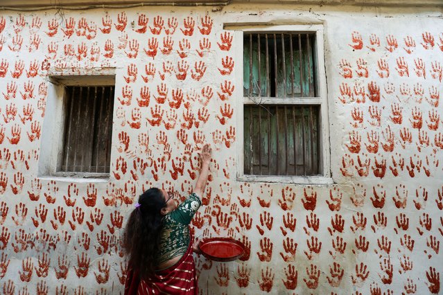 Meenaben Soni makes a red handprint on the wall, on the first day of Navratri during which devotees worship the Hindu goddess Durga, at the old city of Ahmedabad, India on October 3, 2024. (Photo by Amit Dave/Reuters)