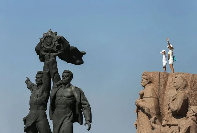 A Ukrainian mother and child stand atop the Friendship of Nations monument in downtown Kiev, Ukraine, 10 August 2015. Meanwhile, the Organization for Security and Cooperation in Europe (OSCE) said 09 August that it has no plans to leave eastern Ukraine after an arson attack destroyed four of the group's armoured vehicles in the separatist stronghold of Donetsk. (Photo by Sergey Dolzhenko/EPA)
