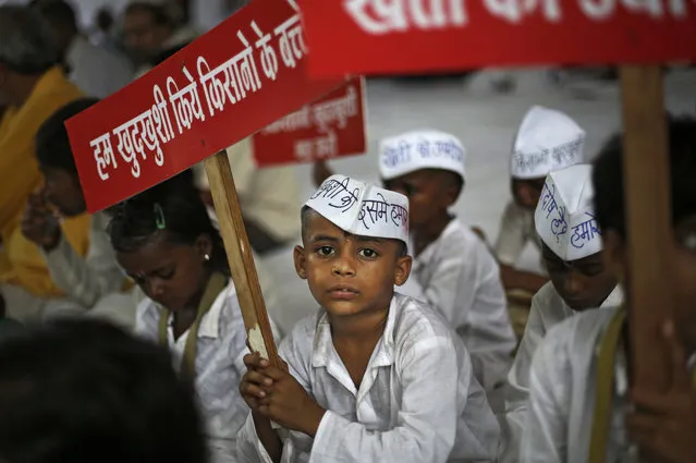 An Indian child wears a cap that reads in Hindi, “My father committed suicide and what is my fault” and holds a placard saying “We are the children of farmers who committed suicide” during a protest against Indian Prime Minister Narendra Modi and his government in New Delhi, India, Wednesday, July 19, 2017. Farmers are demanding better prices for their produce and relief from debts. (Photo by Altaf Qadri/AP Photo)