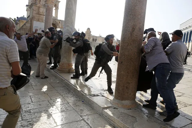 An Israeli police officer aims his weapon at Palestinians during clashes at the Al Aqsa Mosque compound in Jerusalem's Old City, Thursday, July 27, 2017. Israeli Prime Minister Benjamin Netanyahu has ordered police reinforcements deployed to Jerusalem following clashes at a flashpoint holy site. (Photo by Mahmoud Illean/AP Photo)