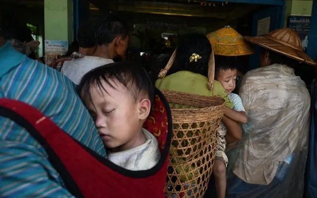 This photo taken on August 25, 2019 shows children being carried as people, affected by clashes between the military and ethnic rebel groups, wait to receive supplies from local civil society organisations in Man Lwal village, outside Kutkai in Shan State. Local civil society organisations say more than 2,000 people have been displaced as residents caught in the middle seek safety in nearby monasteries. (Photo by Ye Aung Thu/AFP Photo)
