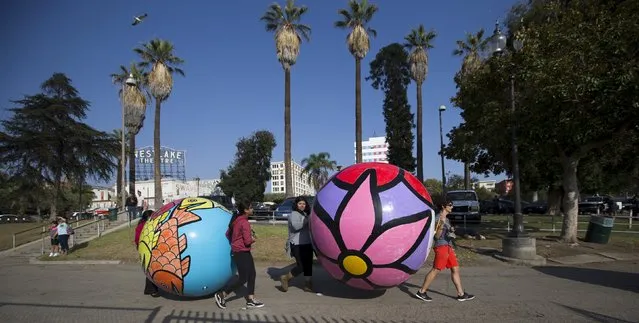 Volunteers carry inflated spheres to be lowered into MacArthur Park Lake during the installation of Portraits of Hope's exhibition “Spheres at MacArthur Park” in Los Angeles, California August 21, 2015. (Photo by Mario Anzuoni/Reuters)
