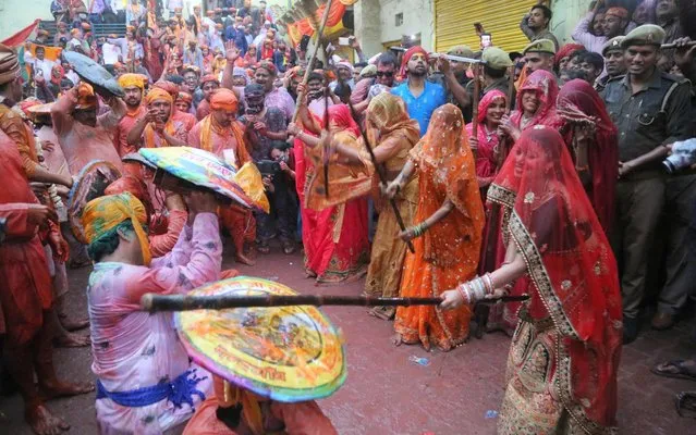 Women beat men with sticks during the Lathmar Holi celebration in the village of Barsana on the outskirts of Mathura in the northern Indian state of Uttar Pradesh on March 4, 2020. Lathmar Holi is a local celebration of the Hindu festival of Holi, usually some days ahead of the Holi festival which is a spring festival, also called 'festival of colours' observed in India at the end of winter season. (Photo by AFP Photo/Stringer)