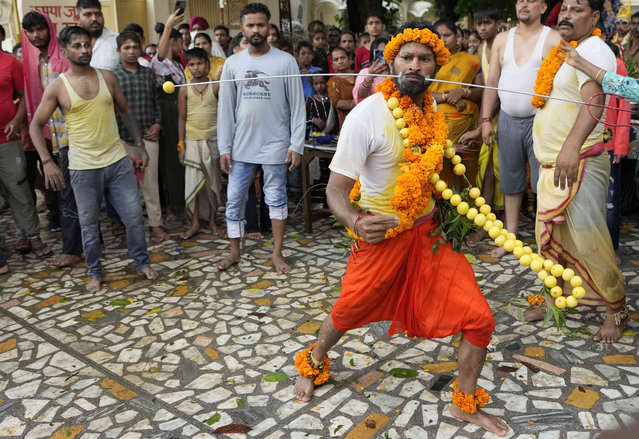 An Indian Hindu devotee dances after piercing a steel rod through his cheeks as part of a ritual during an annual pilgrimage to the temple of Hindu goddess Sheetla Mata in Jammu, India, Sunday, July 24, 2022. (Photo by Channi Anand/AP Photo)
