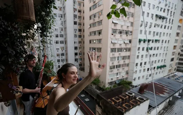 Classical musicians Sofia Ceccato and her husband Simon Bechemin acknowledge thanks as they play for neighbours from their balcony during the coronavirus disease (COVID-19) outbreak, in Rio de Janeiro, Brazil, March 21, 2020. (Photo by Sergio Moraes/Reuters)