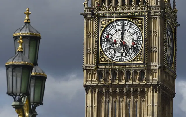 Cleaners abseil down one of the faces of Big Ben, to clean and polish the clock face, above the Houses of Parliament, in central London August 19, 2014. A week has been set aside for the cleaning of what is officially known as the Great Clock, which is set in the Elizabeth Tower. (Photo by Toby Melville/Reuters)