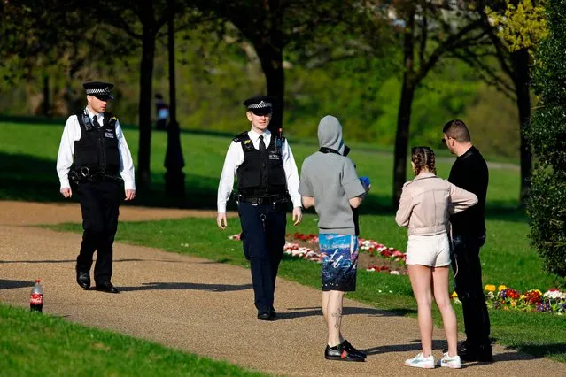Police officers speak to people in Alexandra Park in north London on April 10, 2020 as warm weather tests the nationwide lockdown and the long Easter weekend begins. The disease has struck at the heart of the British government, infected more than 60,000 people nationwide and killed over 8,000, with a daily death toll in England of 866 reported on April 10. (Photo by Tolga Akmen/AFP Photo)