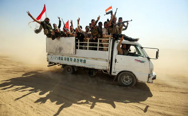 Fighters of the Hashed al-Shaabi (Popular Mobilisation) paramilitaries flash the victory gesture while riding in the back of a truck advancing towards the northern Iraqi town of Sharqat on September 22, 2017. Iraqi forces achieved the first goal of a new offensive against the Islamic State group, penetrating the northern town of Sharqat. Sharqat is the first goal of a major offensive launched to recapture an Islamic State (IS) group-held enclave centred on the insurgent bastion of Hawija in the province of Kirkuk, 300 kilometres (185 miles) northwest of Baghdad, one of just two pockets still controlled by the jihadists in Iraq. (Photo by Ahmad Al-Rubaye/AFP Photo)